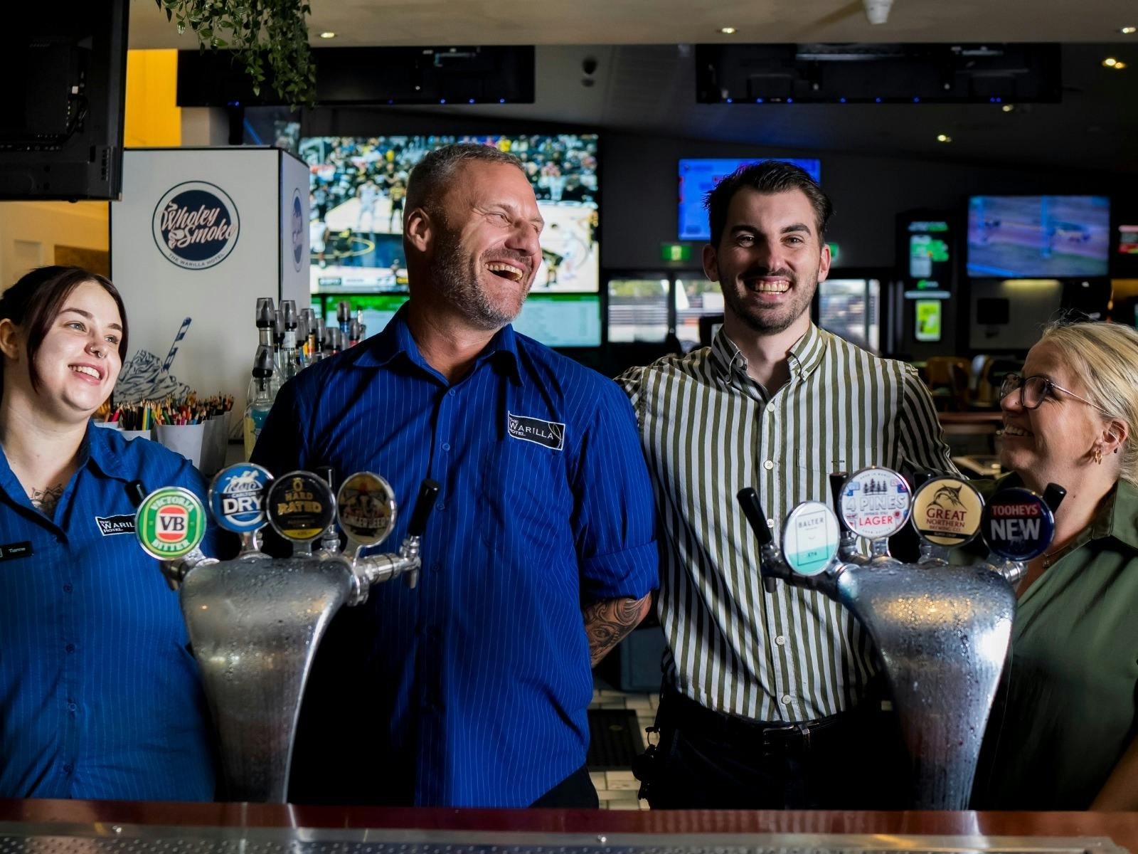 staff members of Warilla Hotel behind the bar smiling and laughing