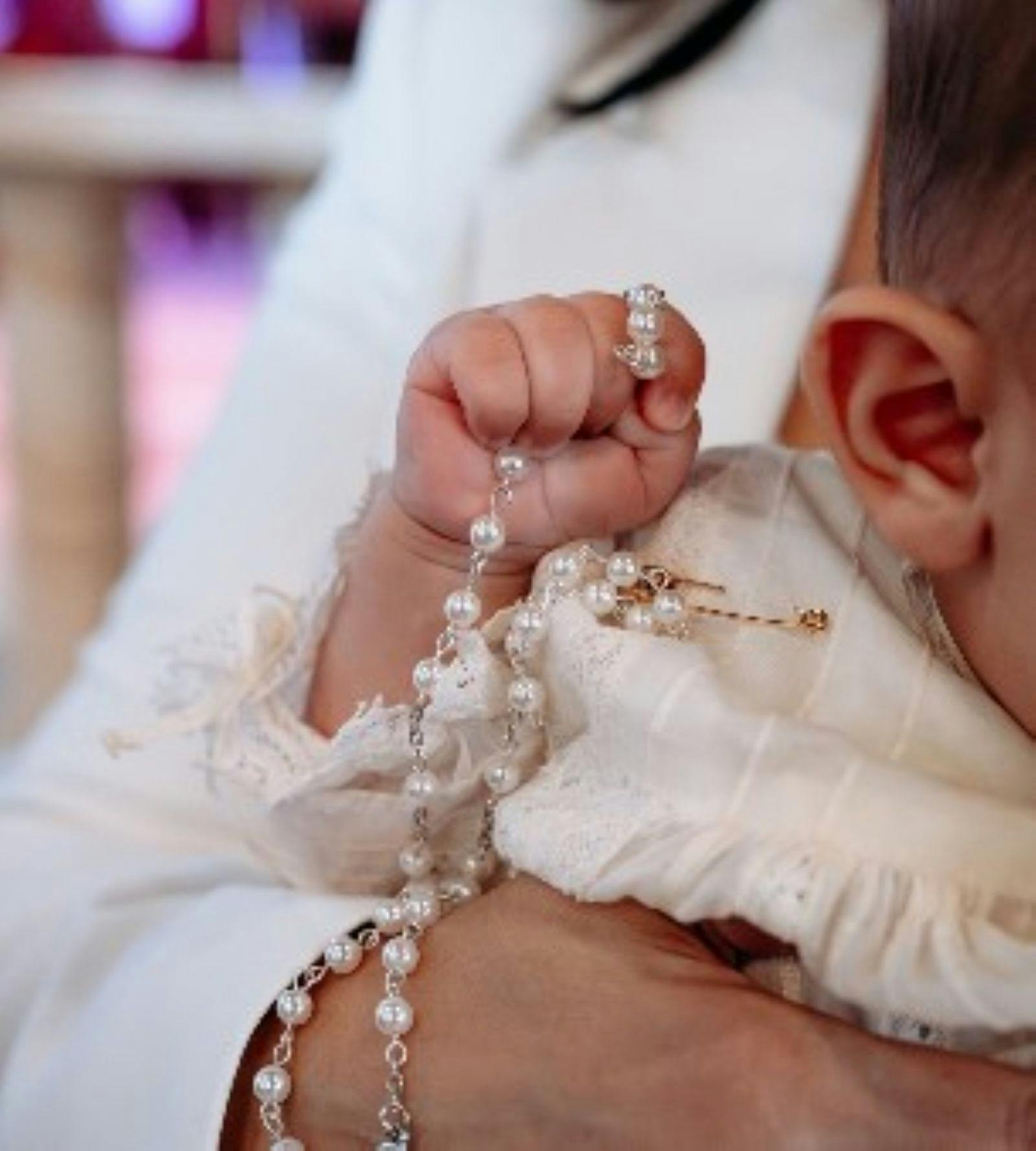 christening baby holding beads
