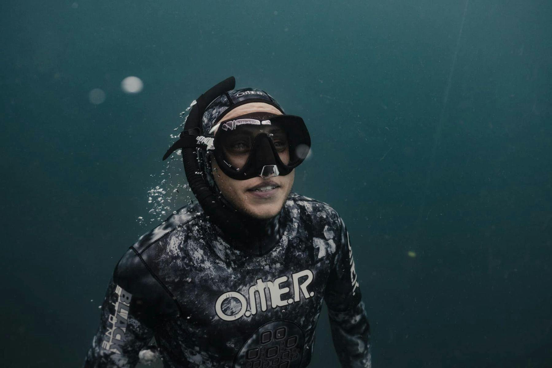 Freediver in the water with goggles under the water