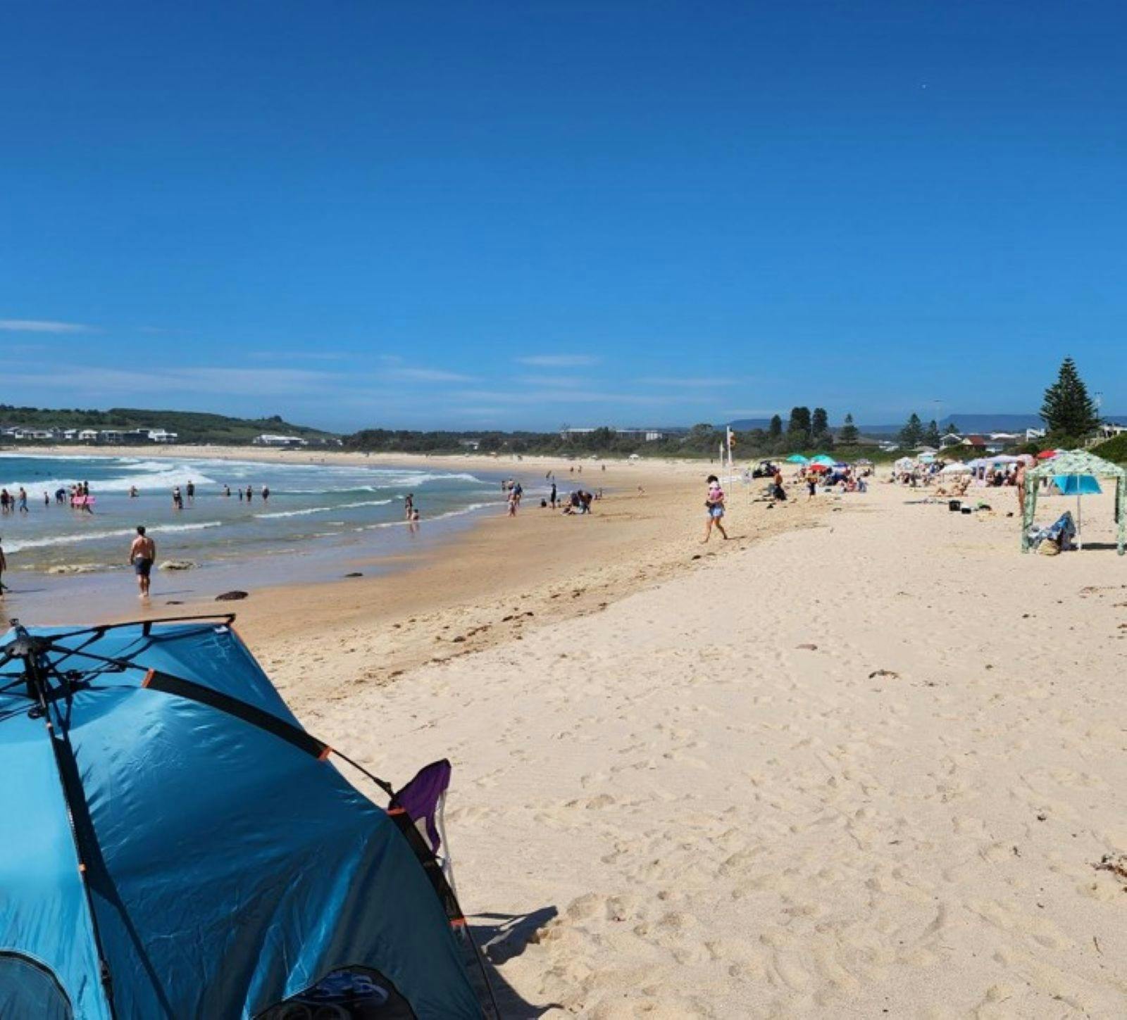 View of beach with people swimming and beach tents