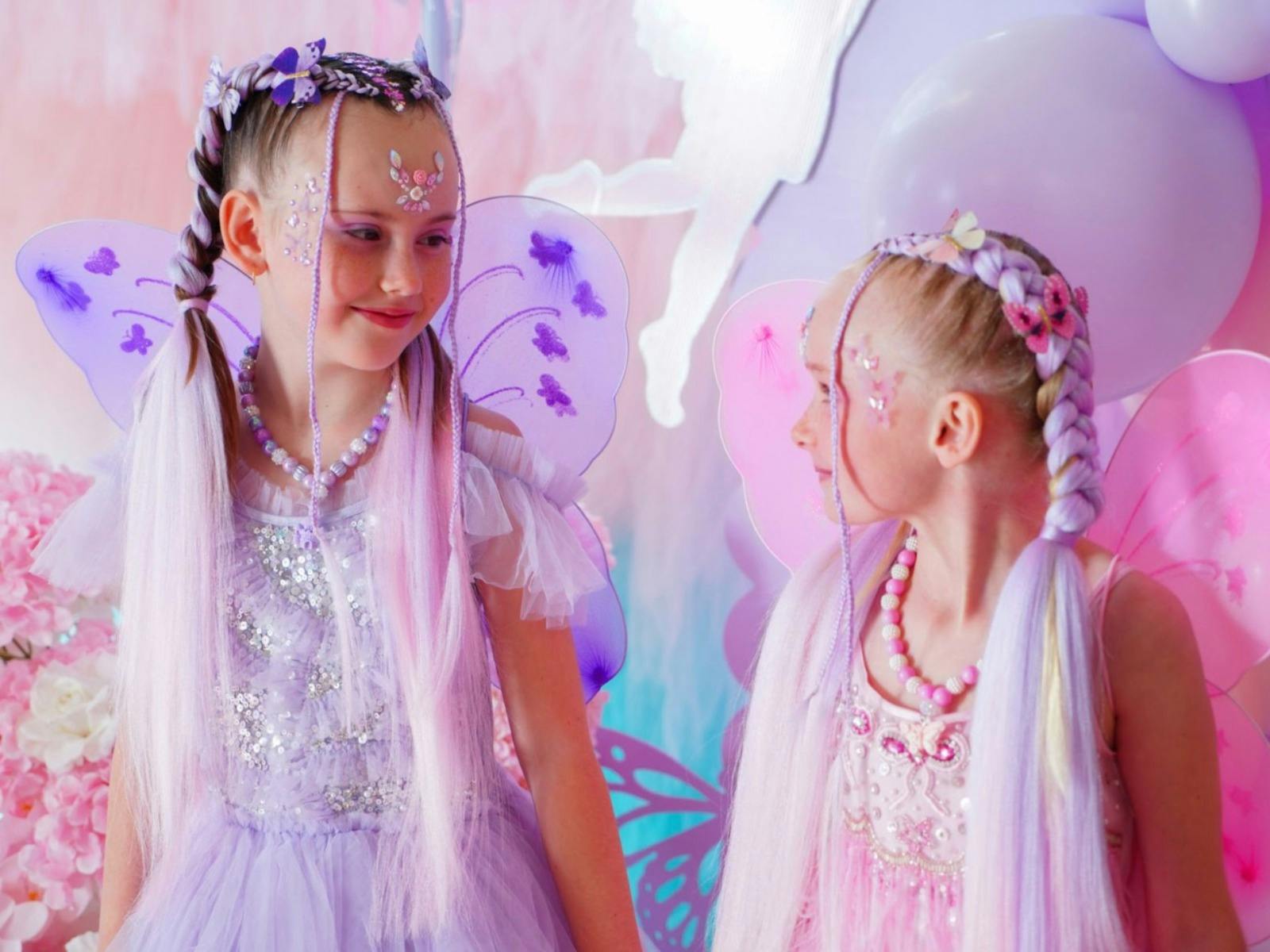 Two young girls with purple and pink dressed up like fairies with lovely manes attached to pony tale
