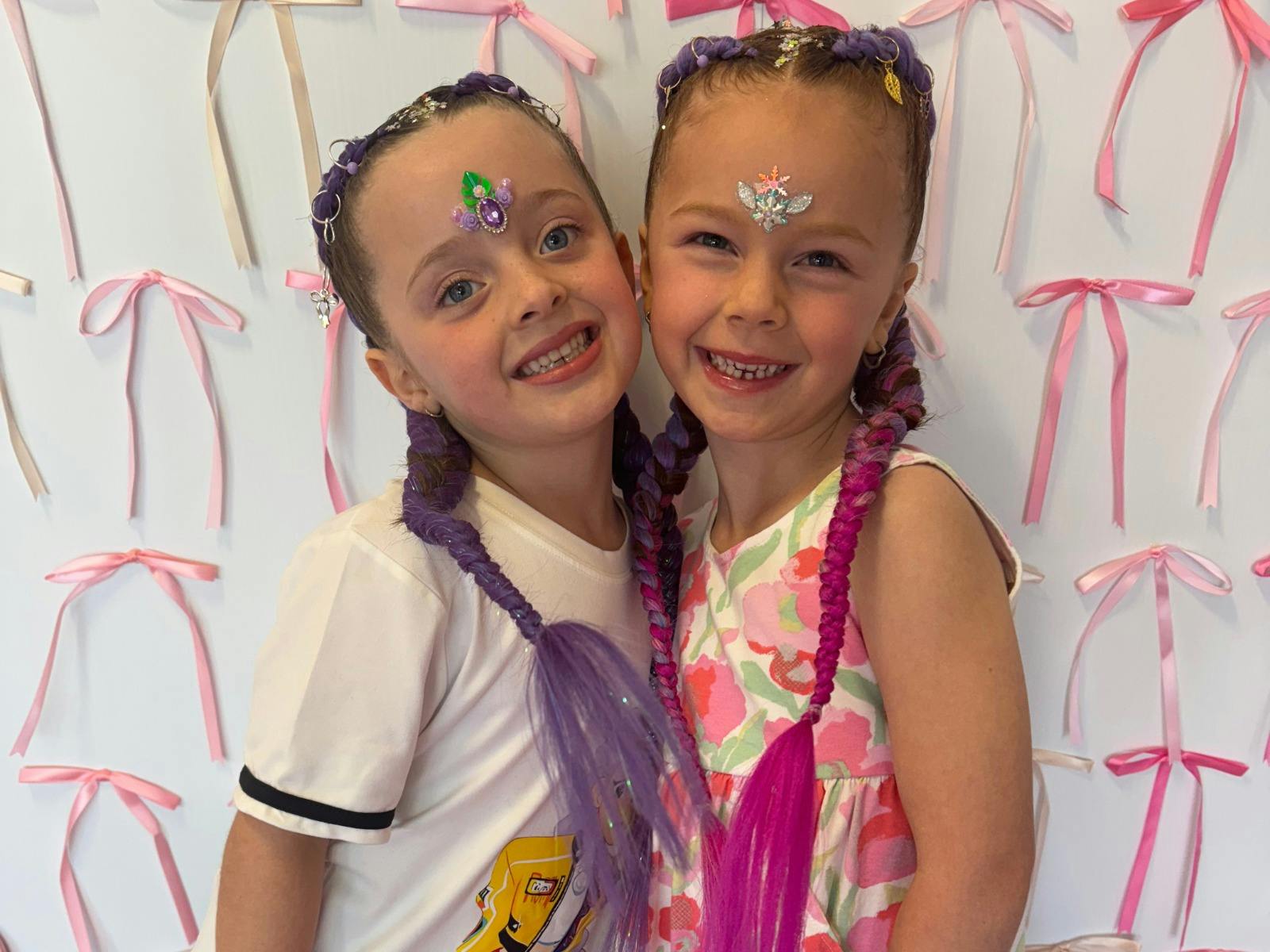 Two young girls with purple and pink manes- braids attached to pony tale