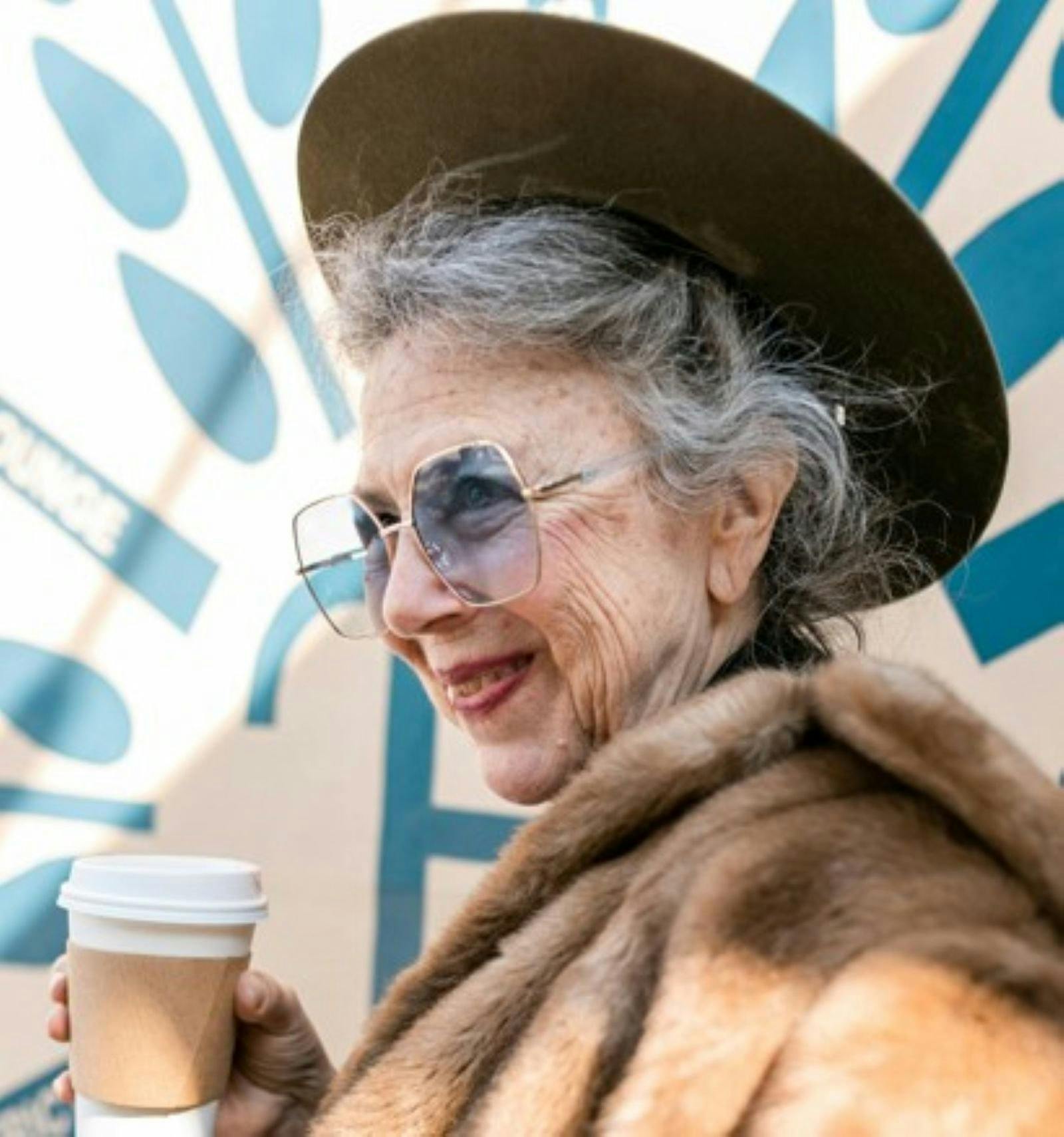 Female Senior folding coffee cup wearing hat