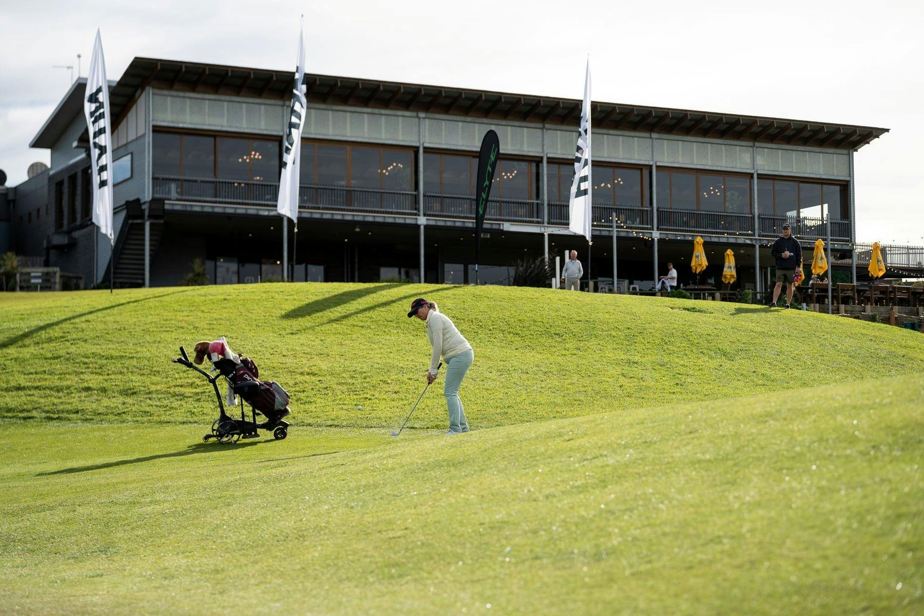Female Golfer on green with Golf club and caddy