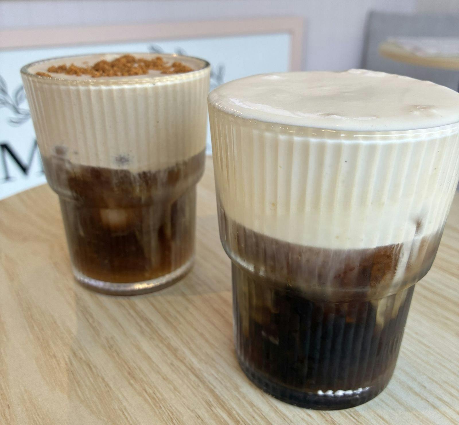 Two cups of warm beverages with a creamy foam and chocolate ontop