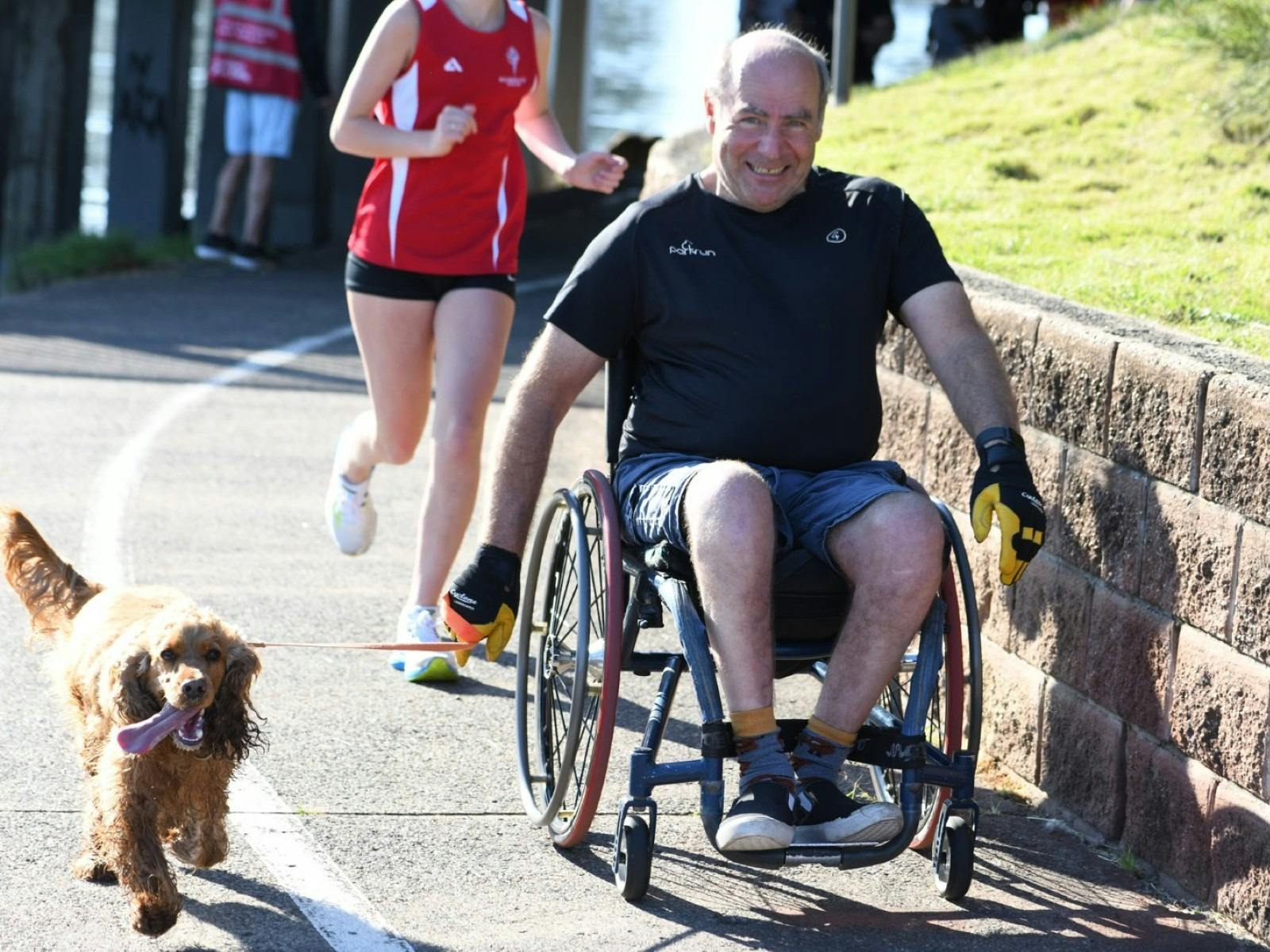 Person in a wheelchair and a dog along doing the Reddall Reserve parkrun
